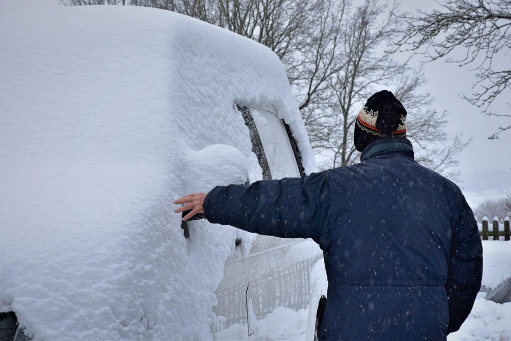 Man touches his snow covered vehicle