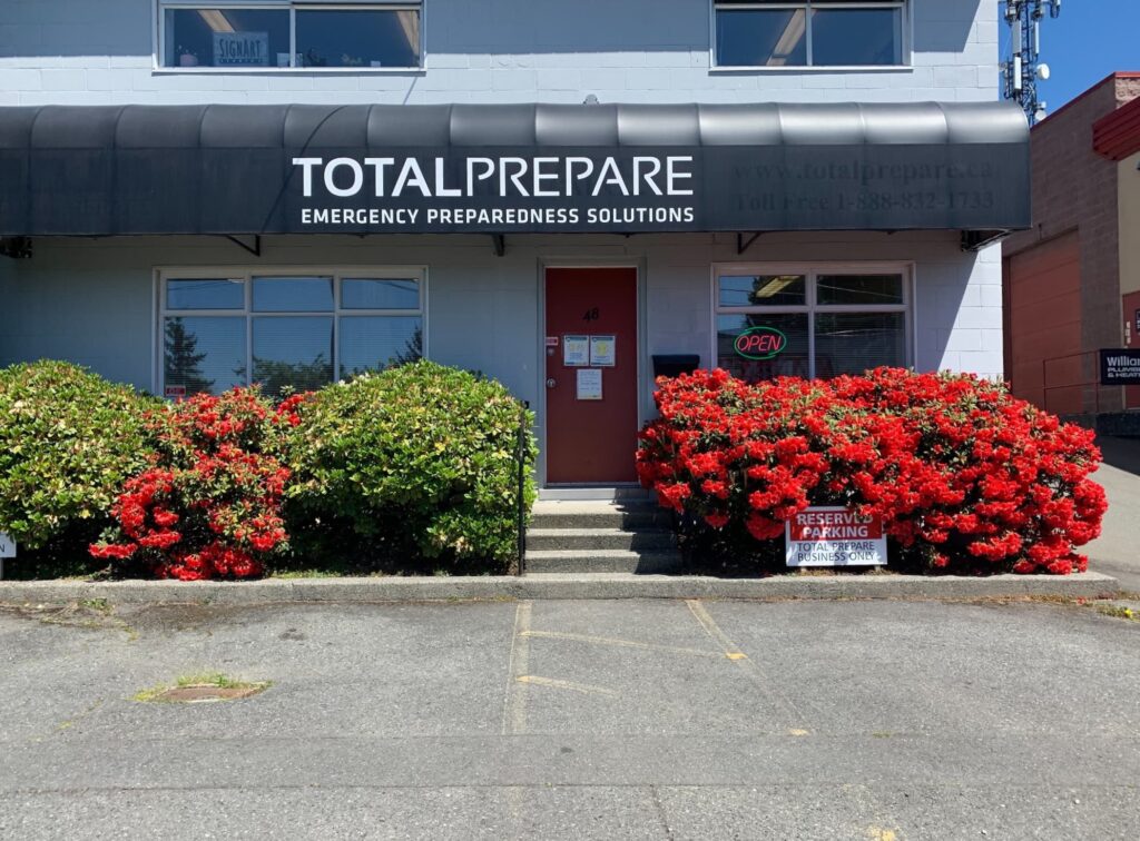 An image of the Total Prepare storefront with a rhododendron bush in bloom.