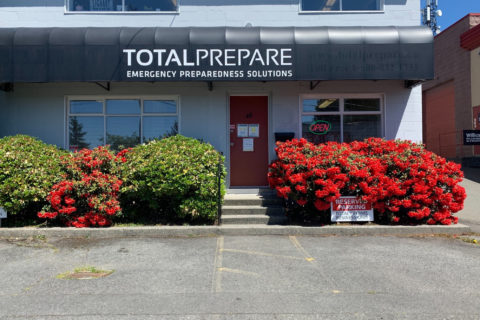 An image of the Total Prepare storefront with a rhododendron bush in bloom.