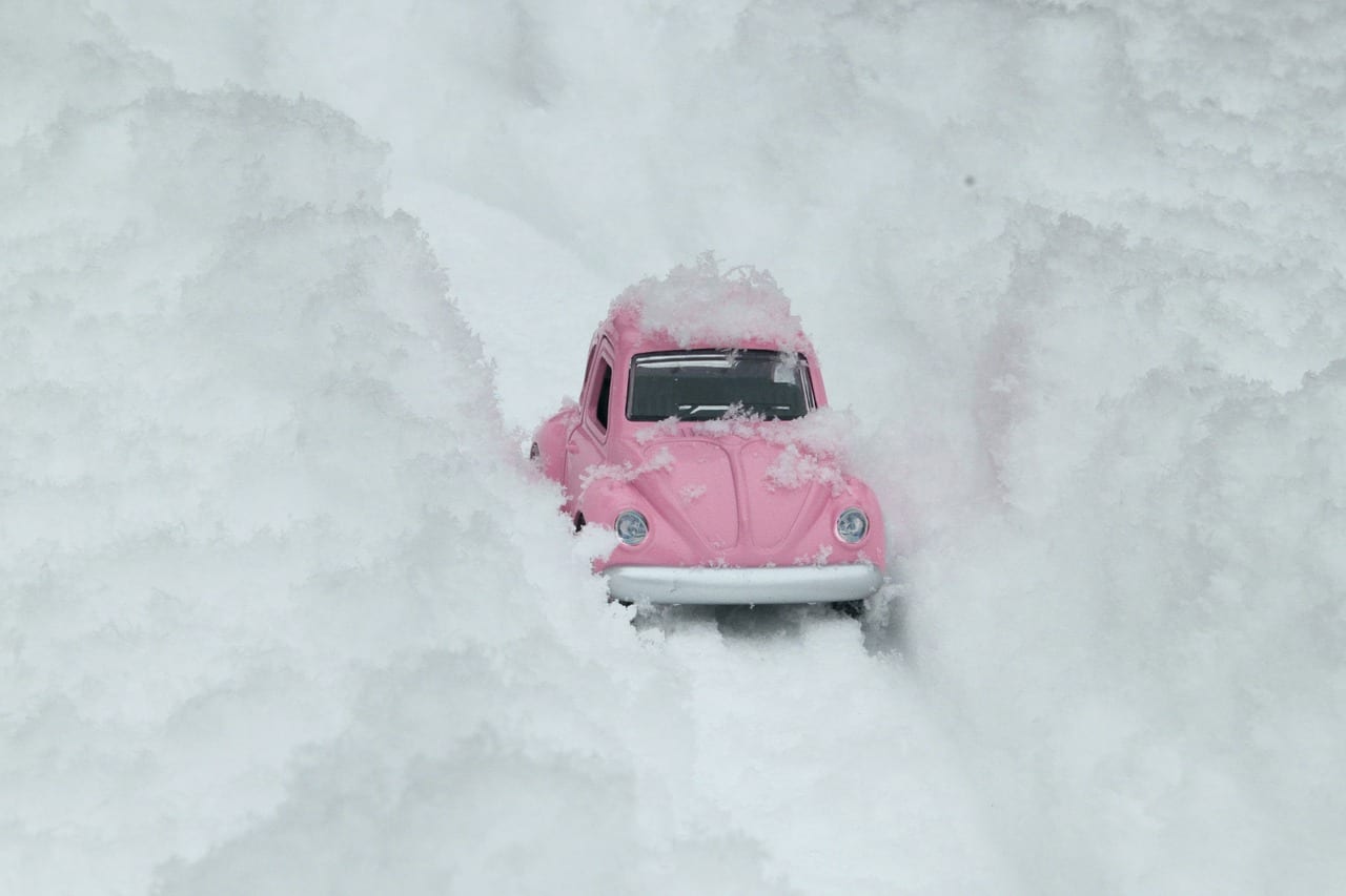 Pink car driving between walls of snow