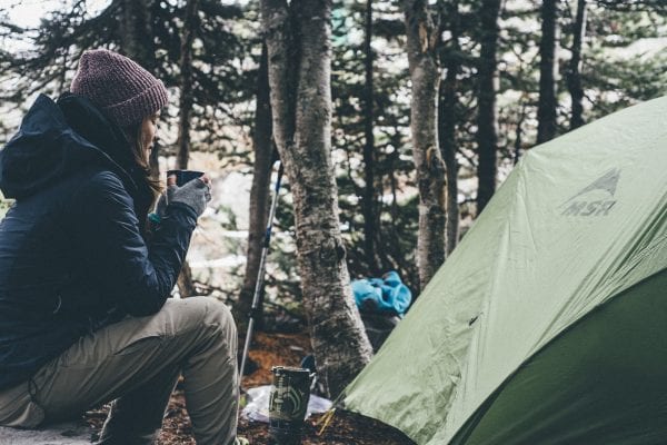 Woman enjoying a cup of coffee at her campsite after a stressful week