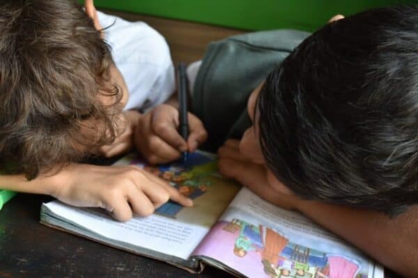 Two children writing in a workbook.