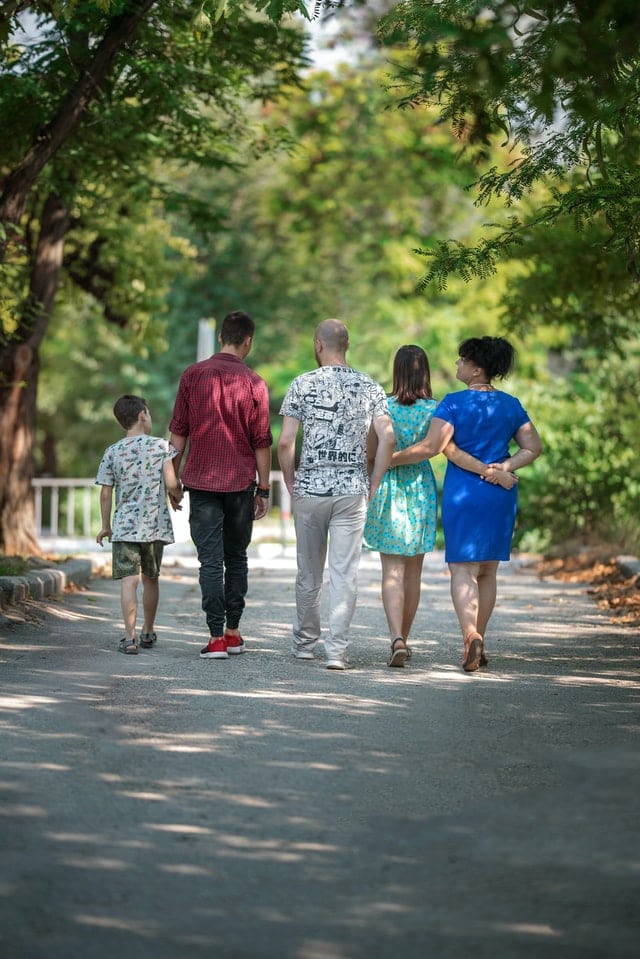 A family facing away from the camera and walking down the road.